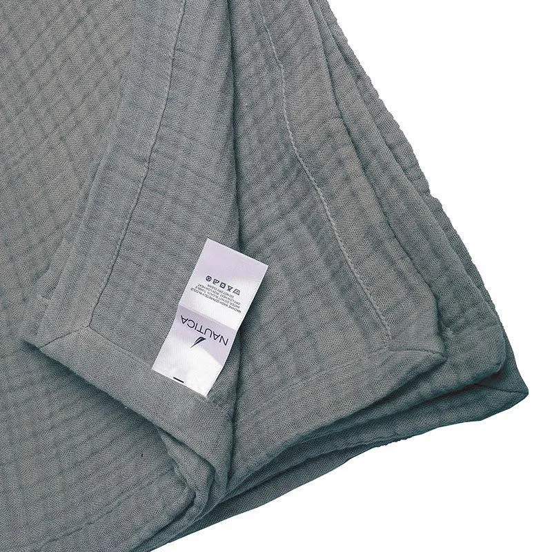 Corner detail of grey bedding showing the textured fabric and care label