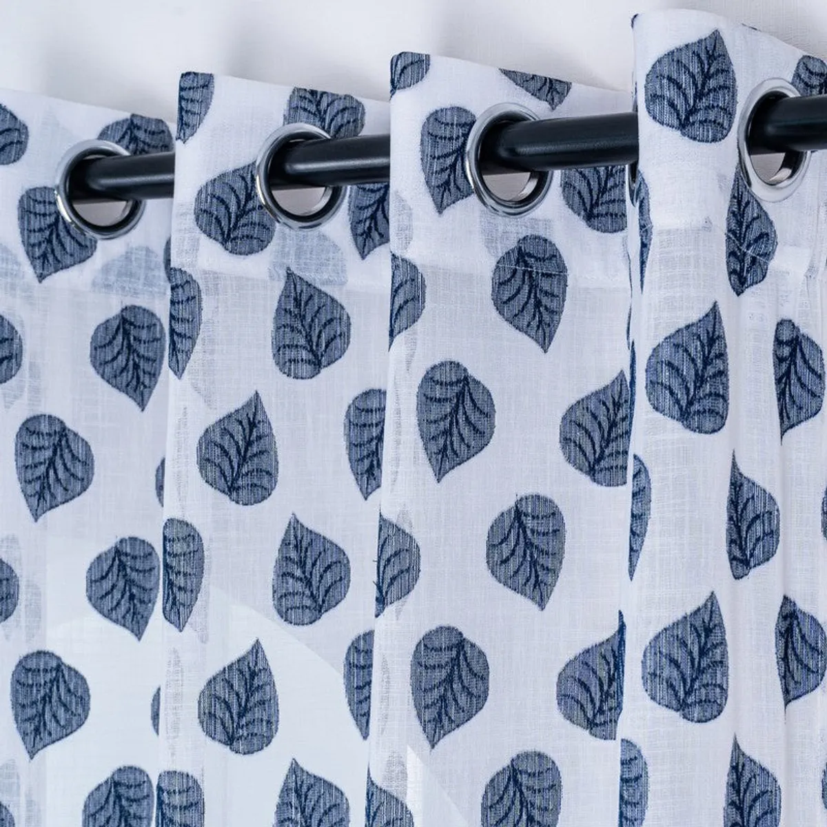 Blue leaf pattern shown across softly gathered curtain fabric.