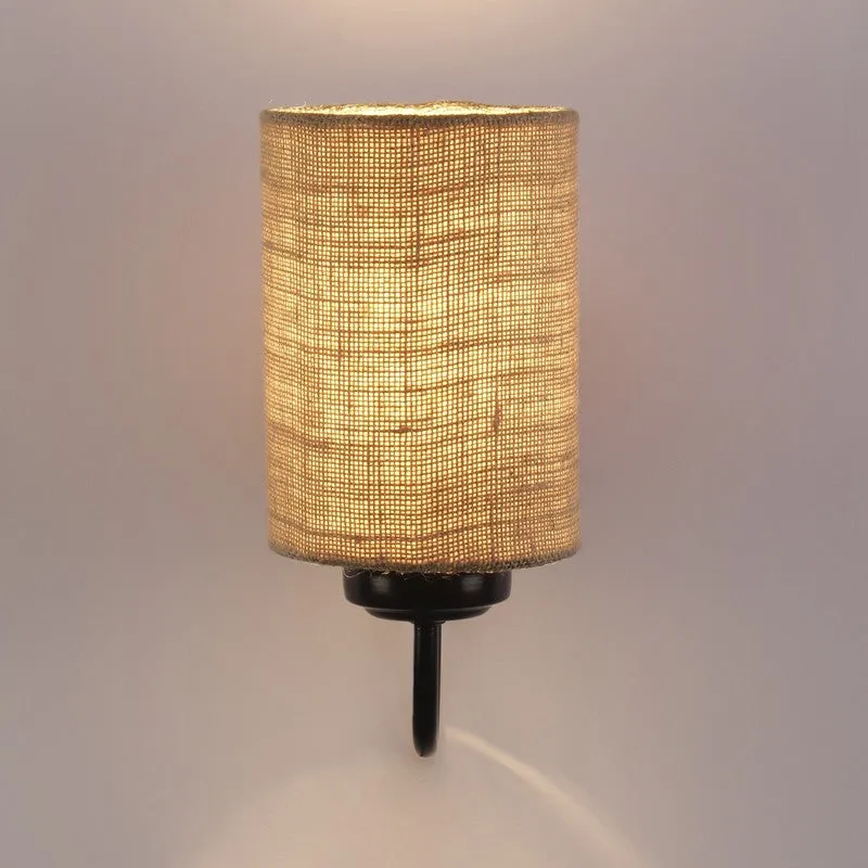 Lit beige jute wall lamp with black iron fitting on a plain wall