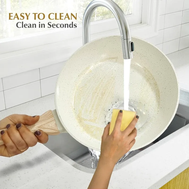 White speckled frying pan being rinsed and cleaned in a sink