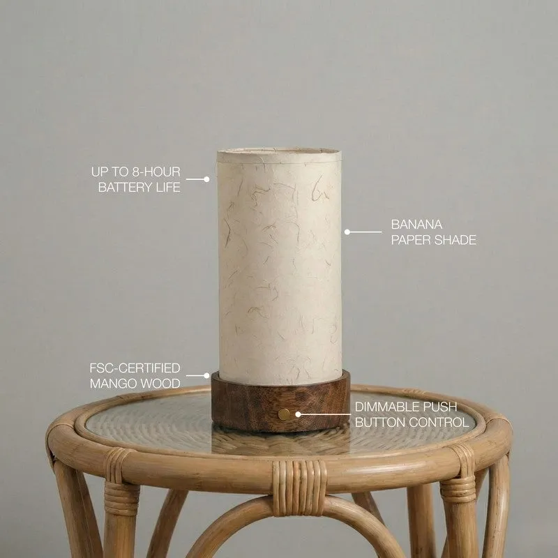 Ivory cylindrical lamp with wooden base shown on a round side table