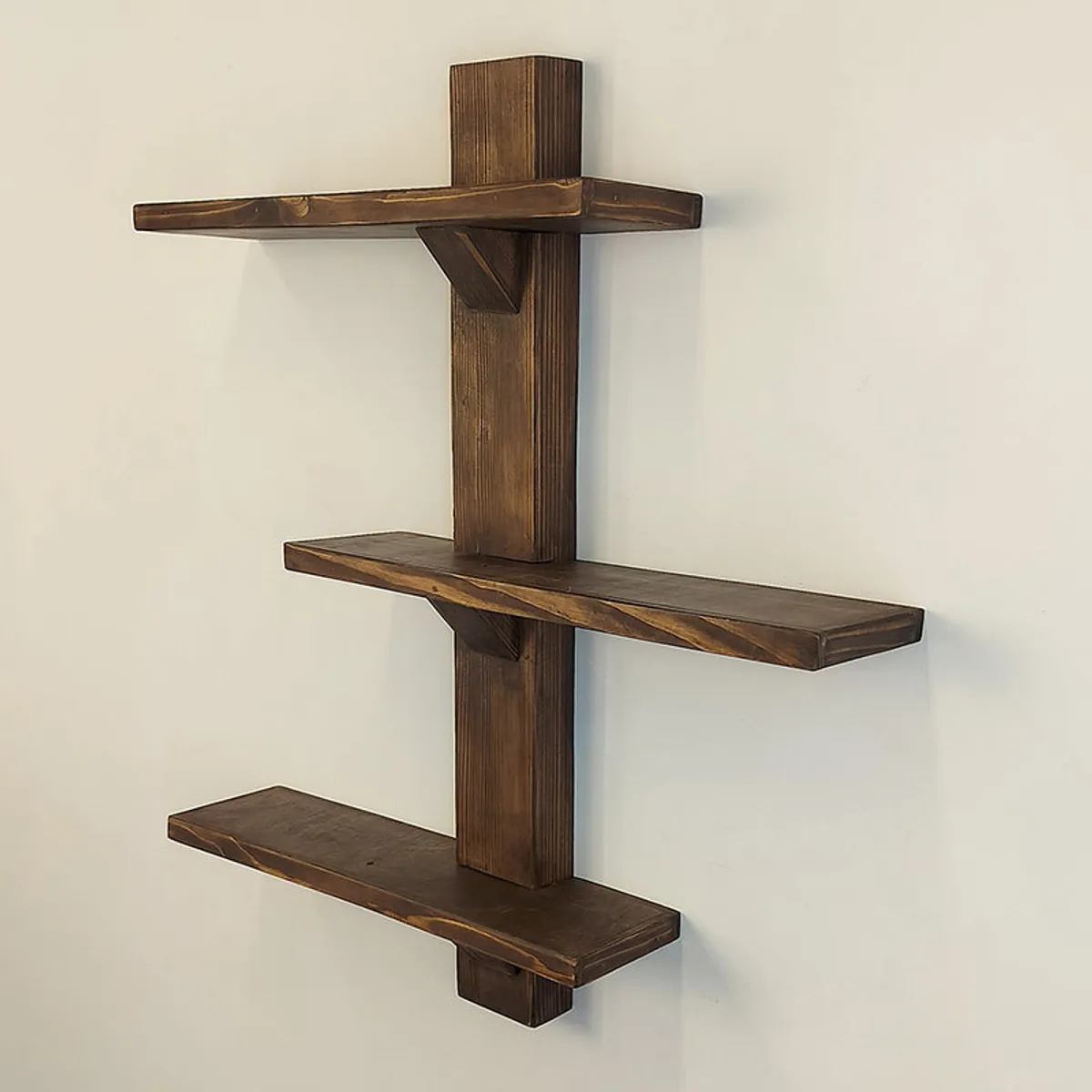 Unstyled brown wooden wall shelf organiser showing three staggered tiers.