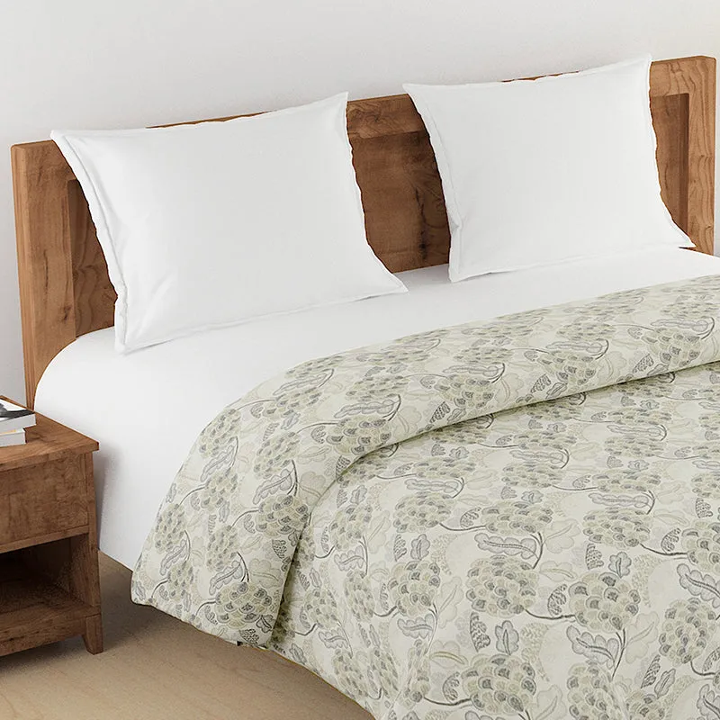 Close view of grey floral comforter on a bed with white pillows