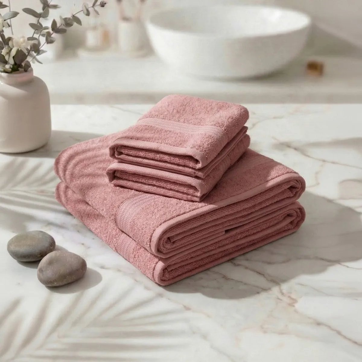 Folded pink towel set stacked on a marble surface