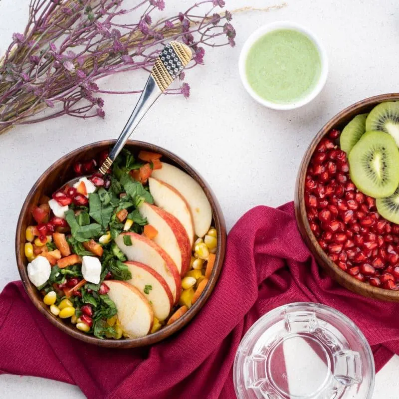 Wooden bowls filled with salad and fruit on a styled table setting