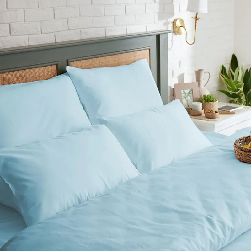 Two pale blue pillow covers styled on a bed with matching light blue bedding.