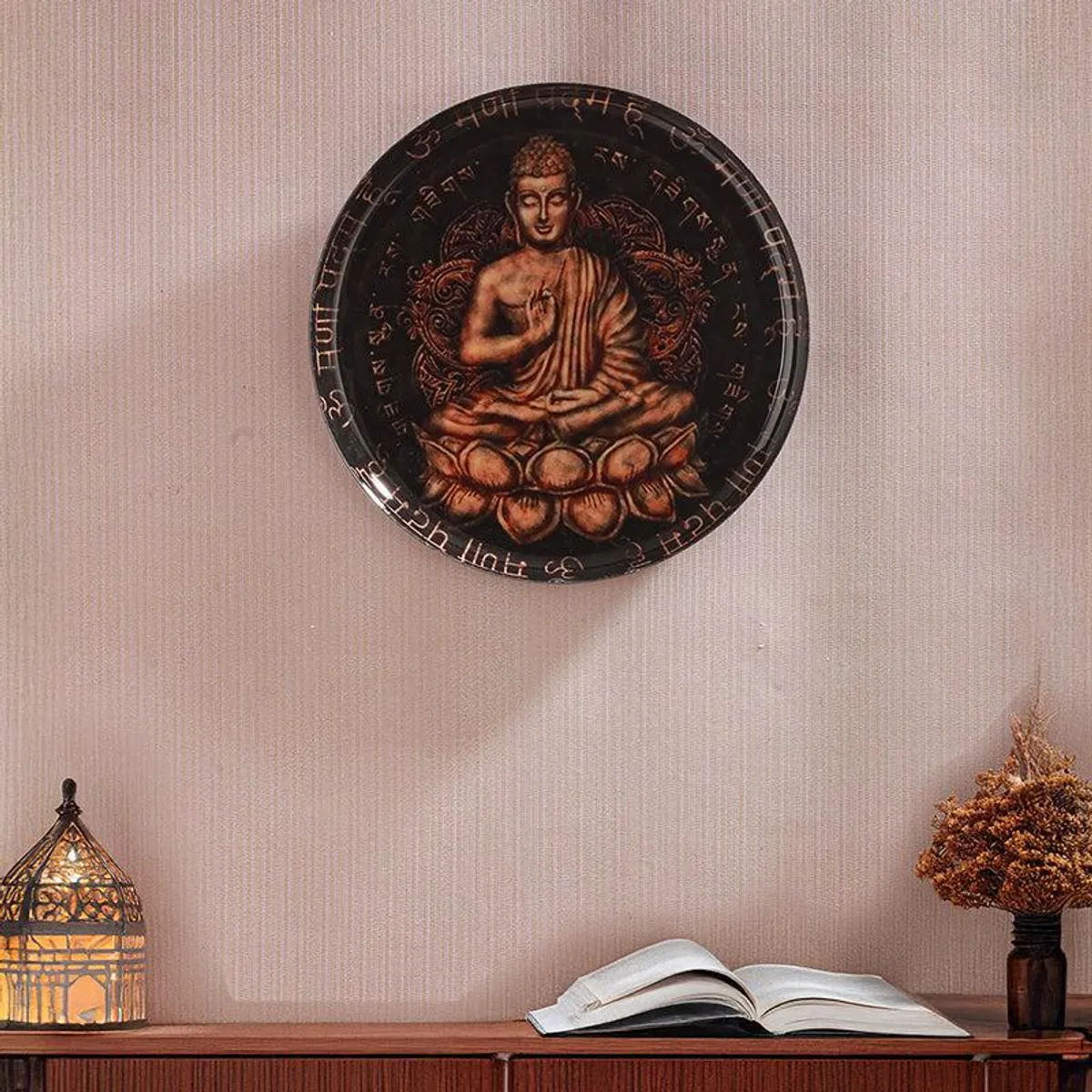 Buddha wall plate mounted on a textured wall above a console and open book