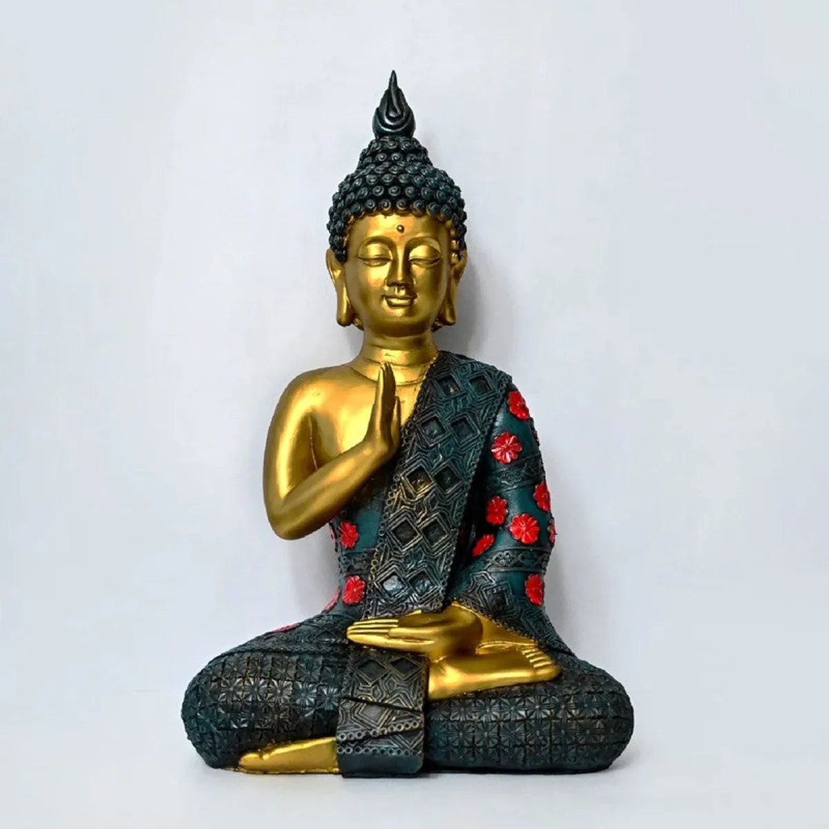 Front view of a golden Buddha idol with textured teal drape and red accents