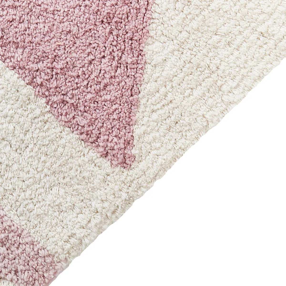 Close-up of the rug's soft tufted texture and pink geometric pattern