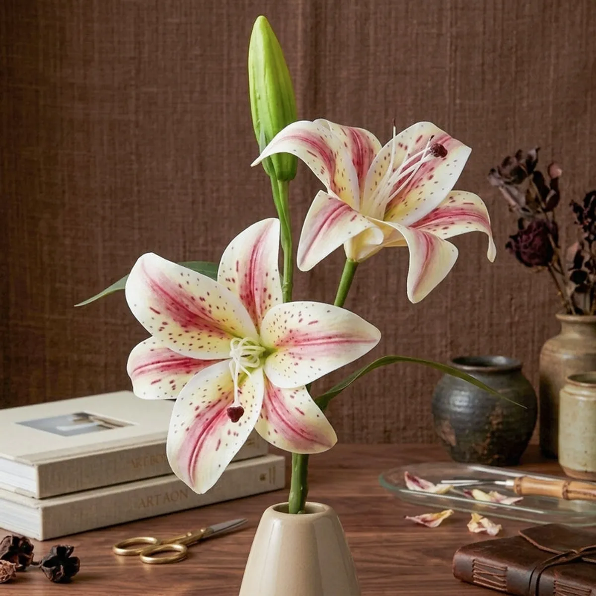 White and pink artificial lily flower stick styled in a vase against a dark background