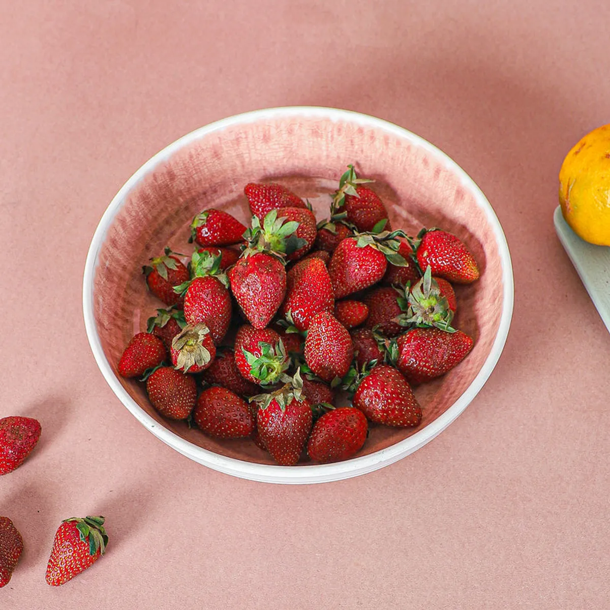 Top view of a white and pink bowl filled with fresh strawberries