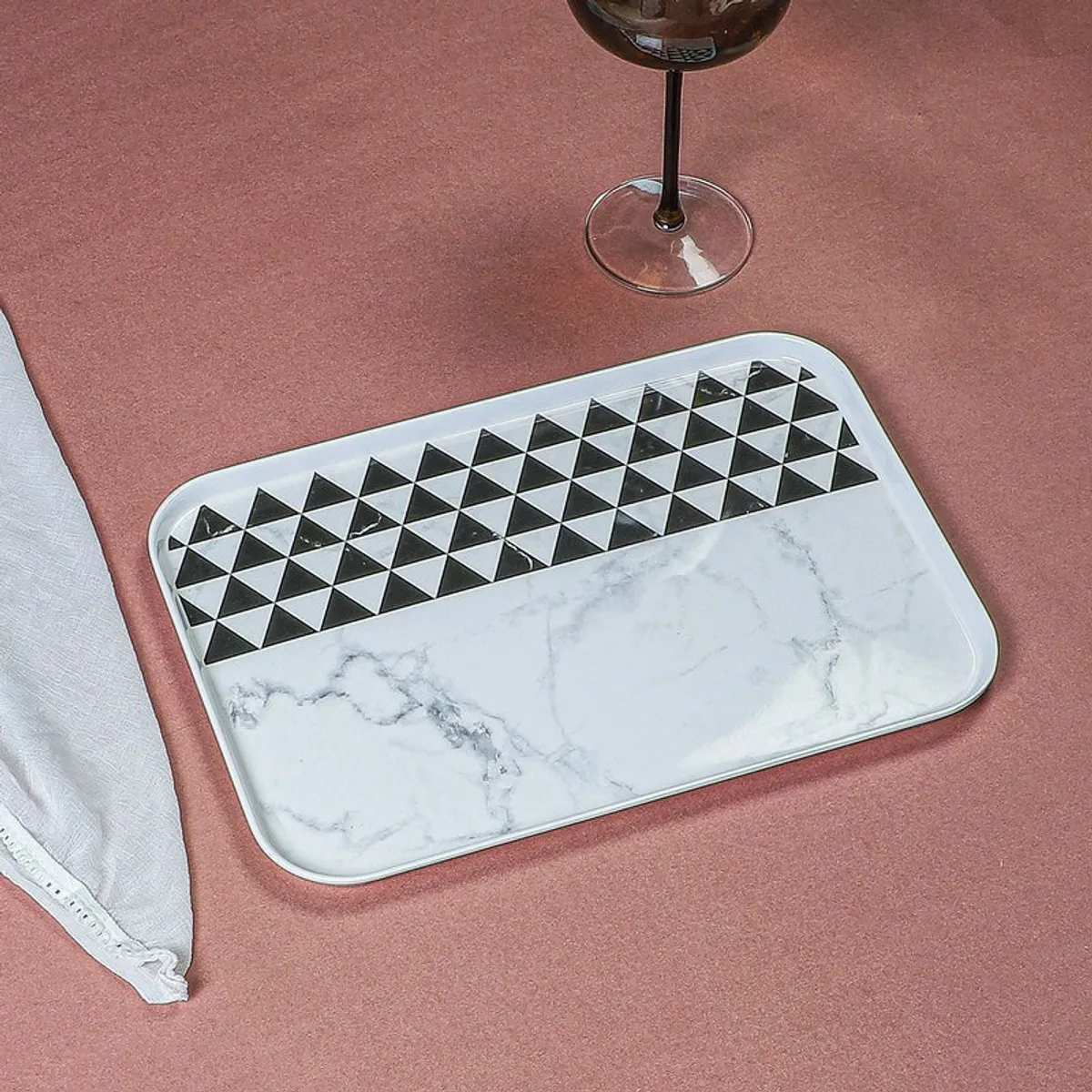 Black and white geometric tray on a table beside a folded napkin