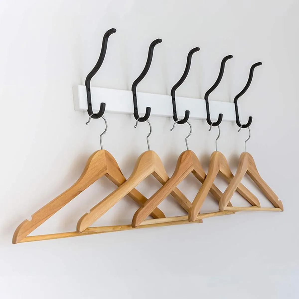 Wooden hangers arranged on wall-mounted hooks