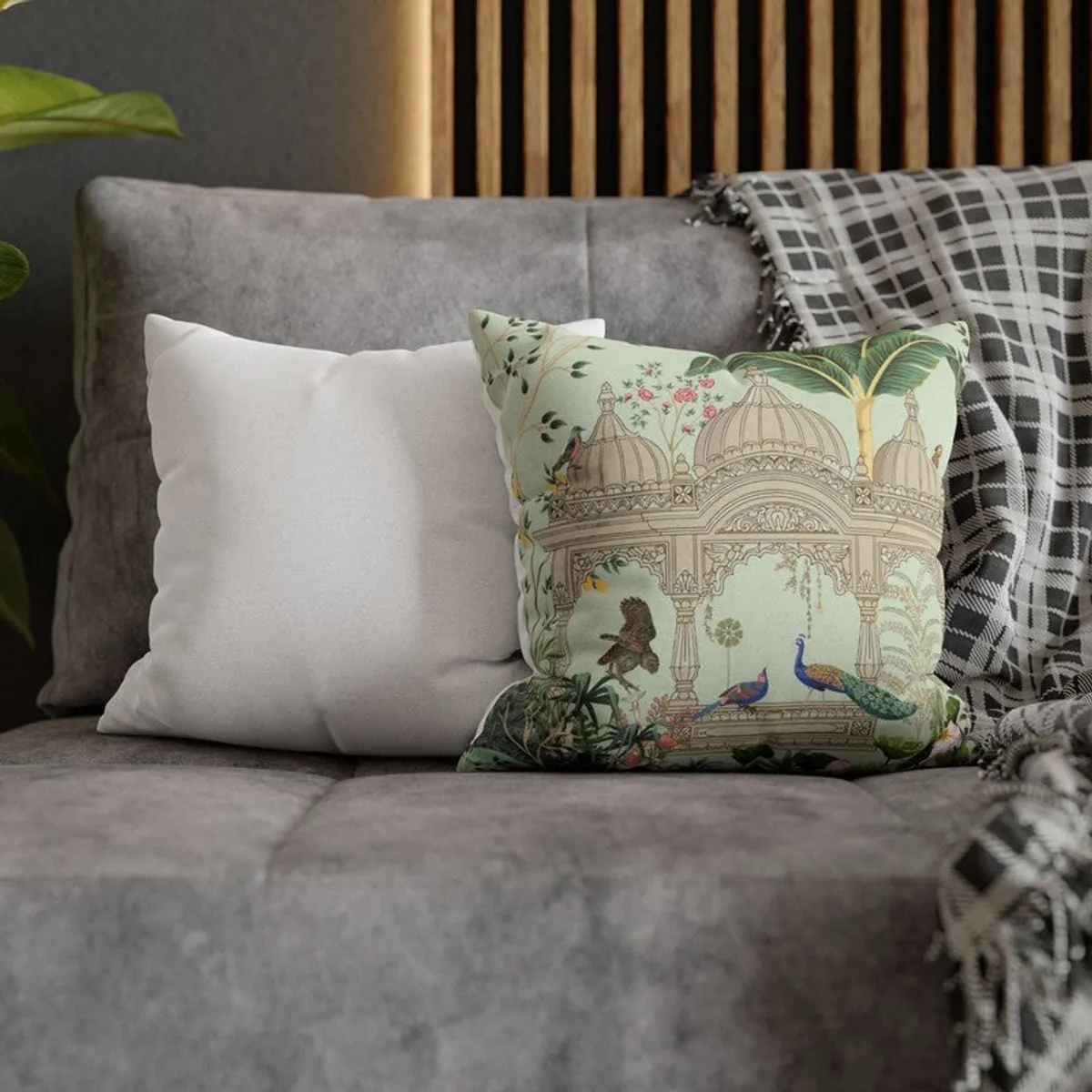 Mint peacock cushion cover layered with neutral cushions on a grey sofa