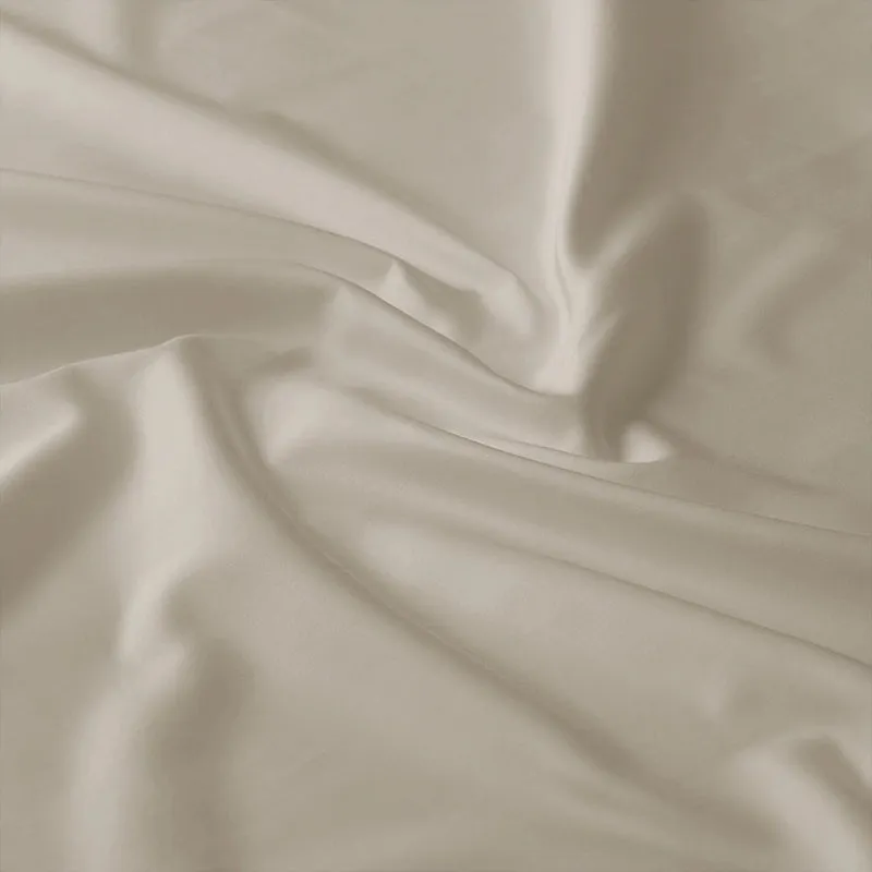 Close-up view of the smooth beige cotton bedsheet fabric