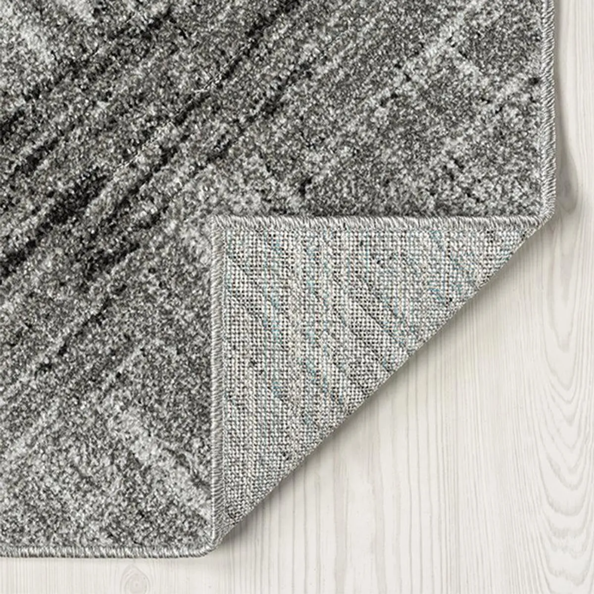 Close-up of the grey carpet corner showing surface texture and backing