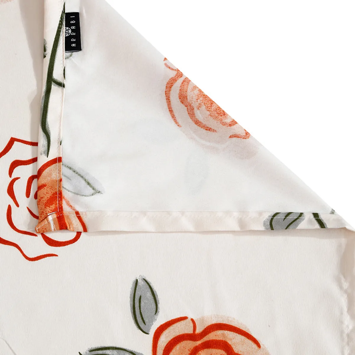 Folded corner of ivory floral bedsheet showing the printed fabric and hem
