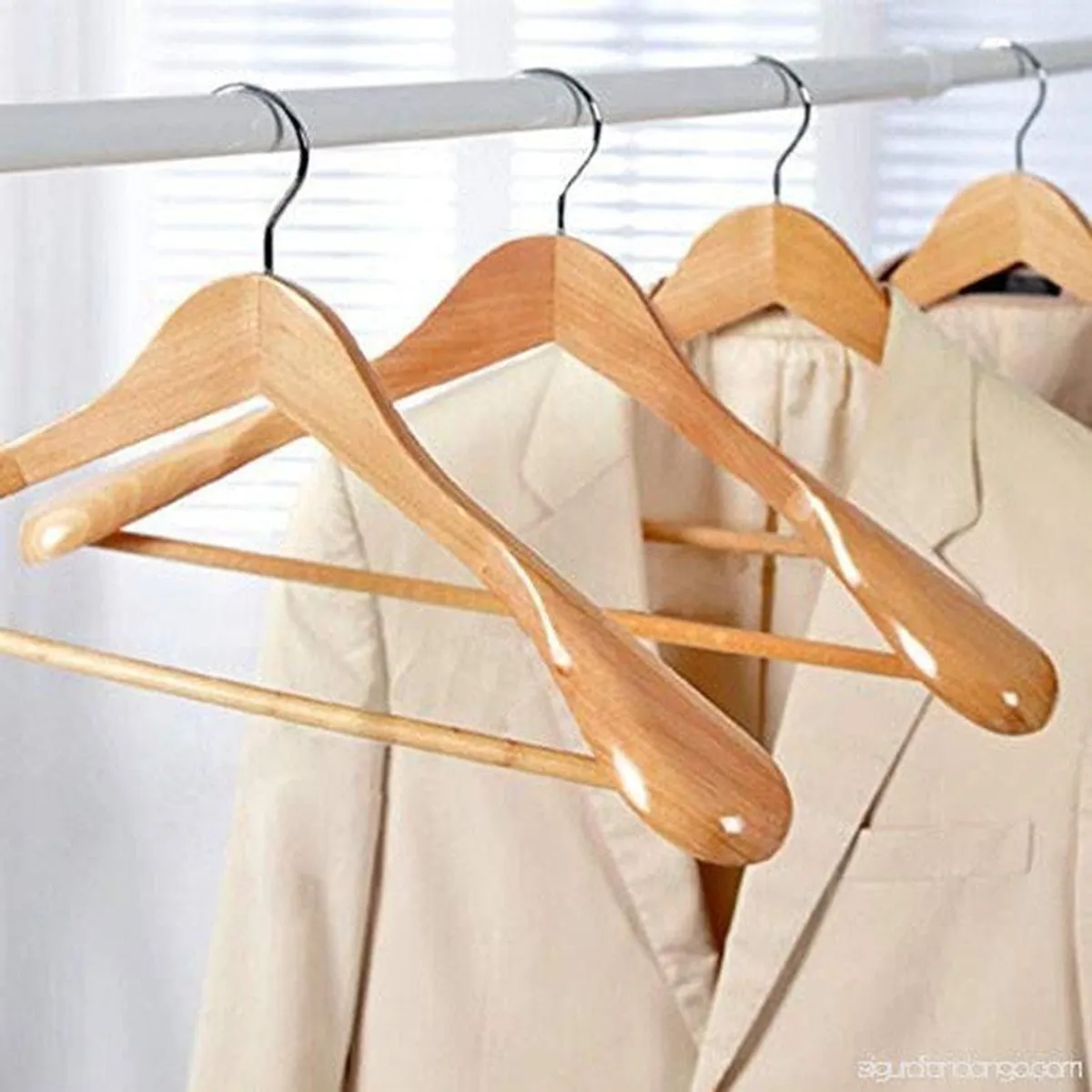 Wooden hangers on a rail with light-coloured jackets