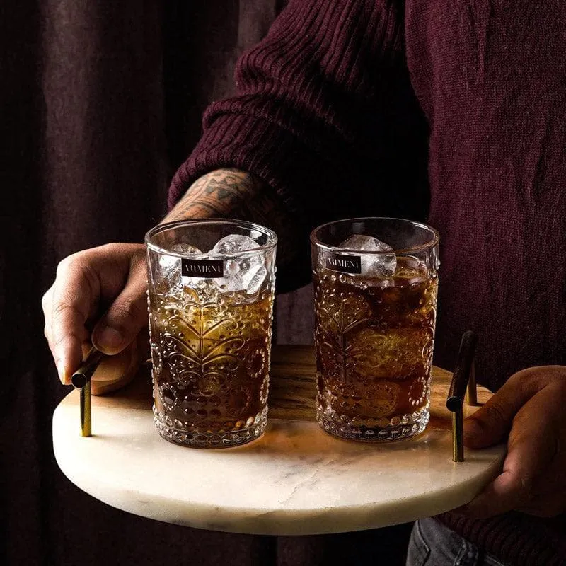 Two embossed clear glasses with iced drinks on a round tray