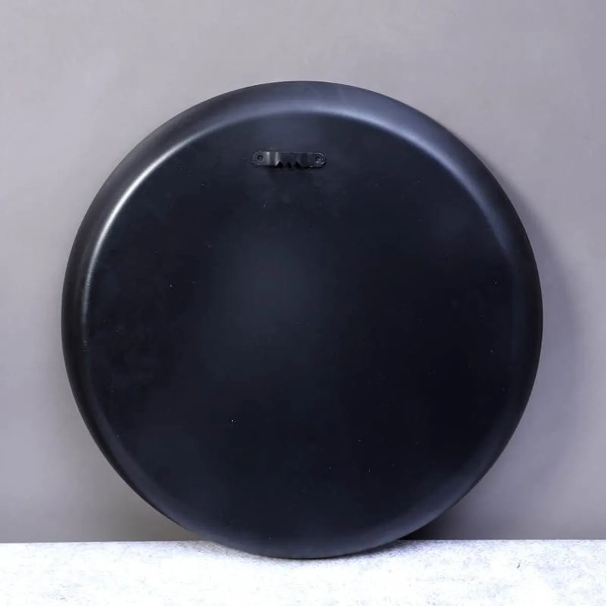 Back of the round black wall plate showing its wall-mount fitting