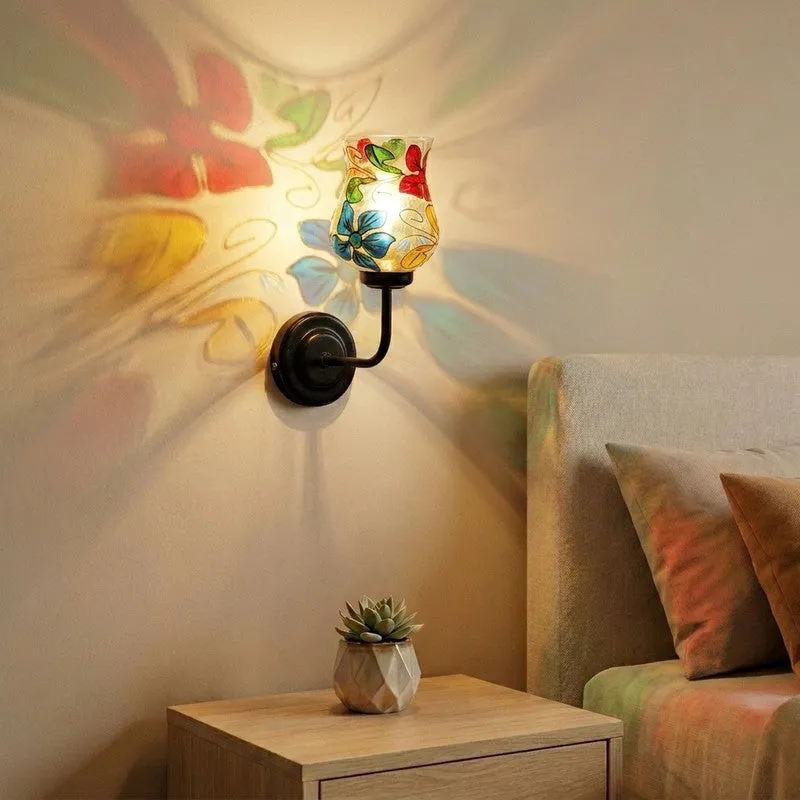 Floral mosaic glass wall lamp casting colourful light on a wall beside a sofa