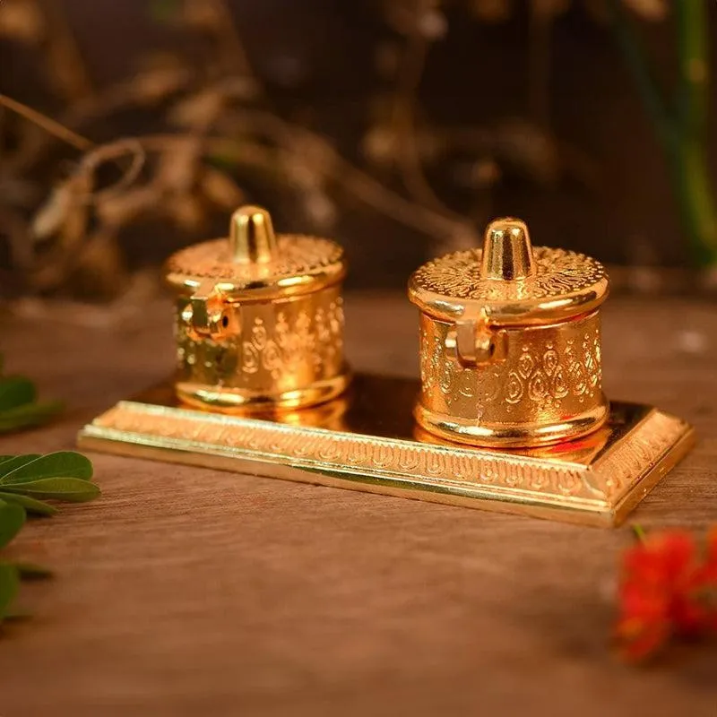 Angled view of a gold pooja tray with two decorative lidded containers