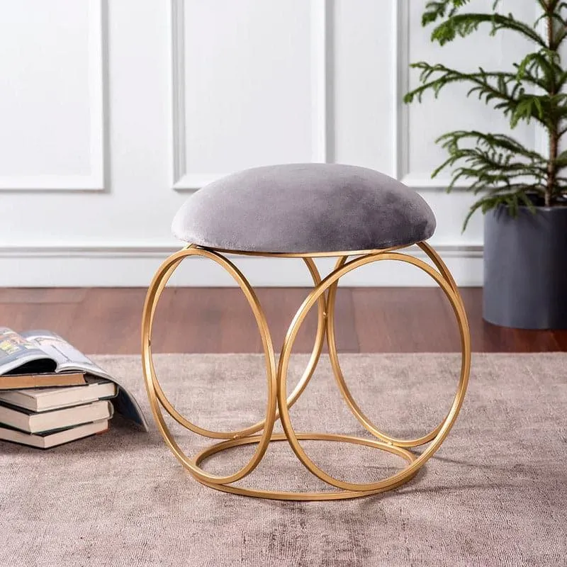 Grey velvet stool with circular gold frame in a living room setting
