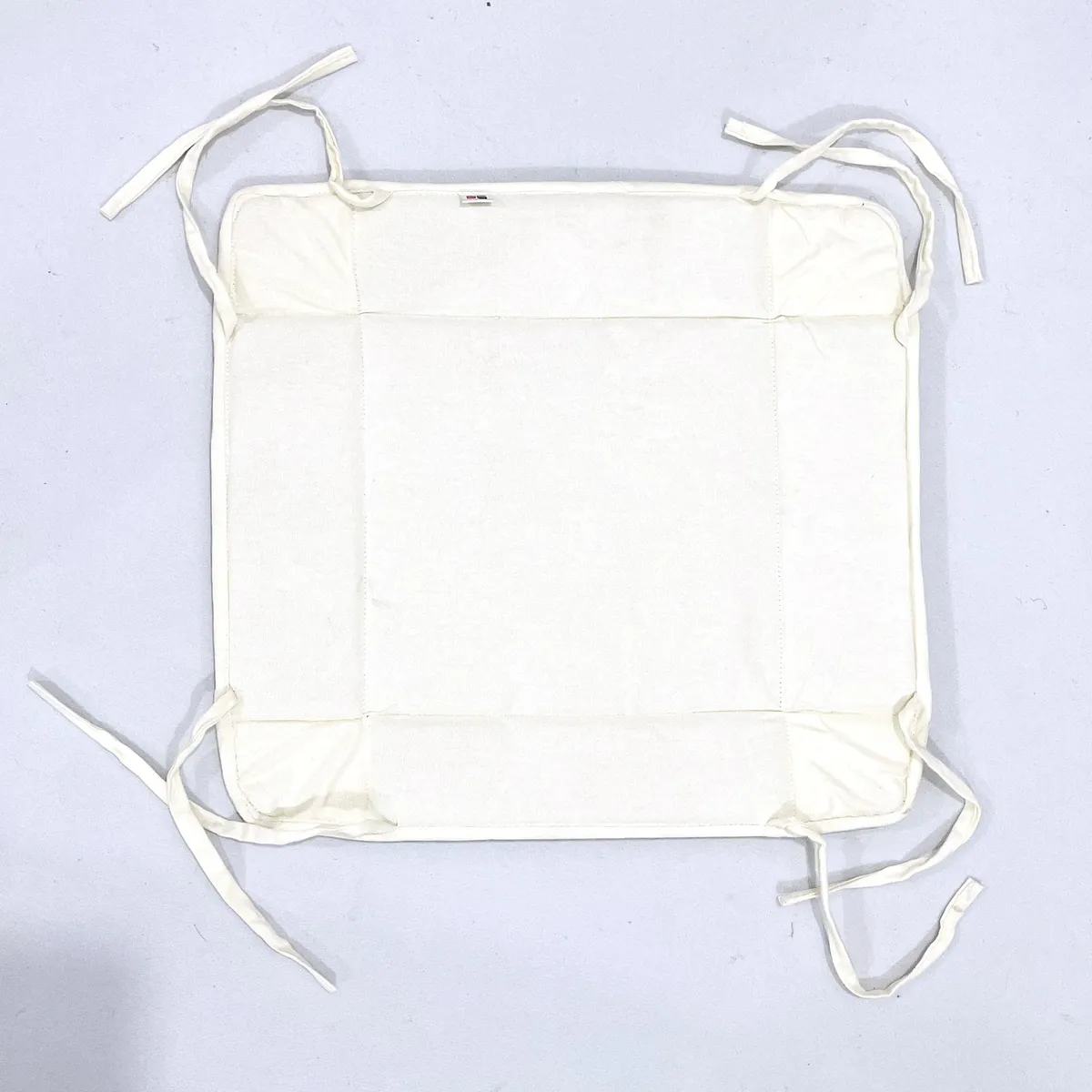 Flat cream fabric bread basket with corner ties laid open