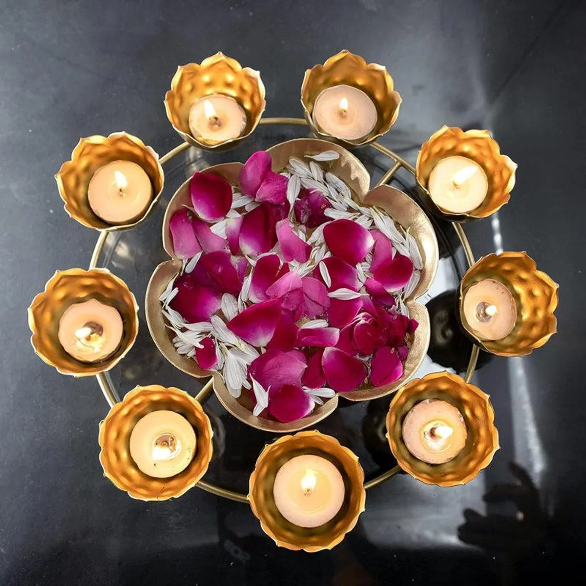 Gold flower urli filled with petals and surrounded by lit candles