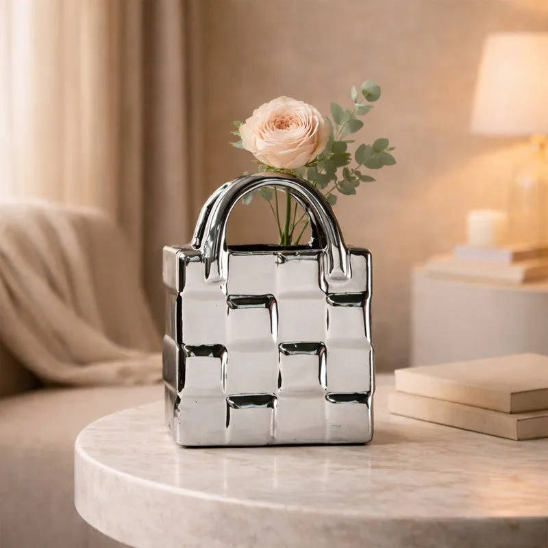 Silver handbag-shaped vase with a blush rose on a round marble table