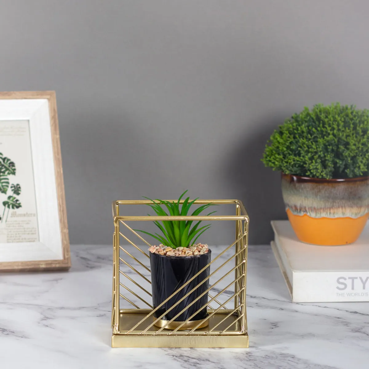 Front view of gold metal planter with black pot and faux green plant