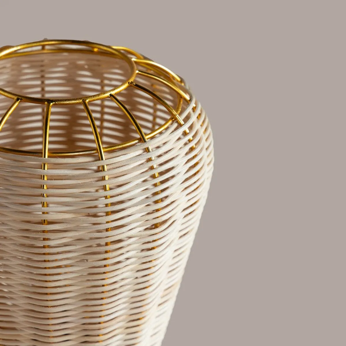 Detailed view of the beige rattan shade with gold metal framing