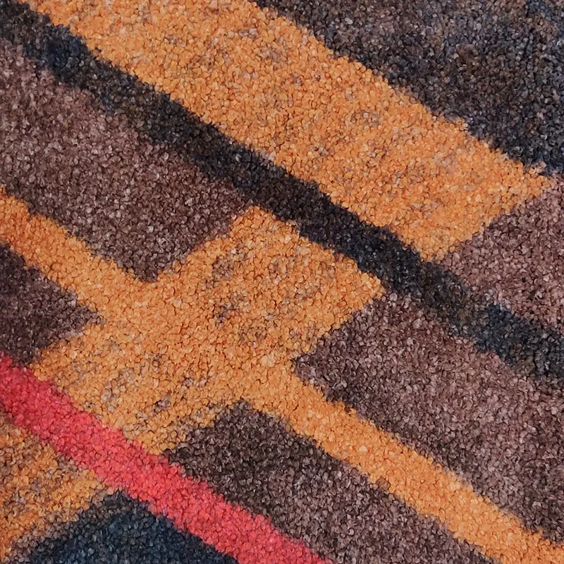 Close-up of the rug's brown, tan and red geometric surface texture