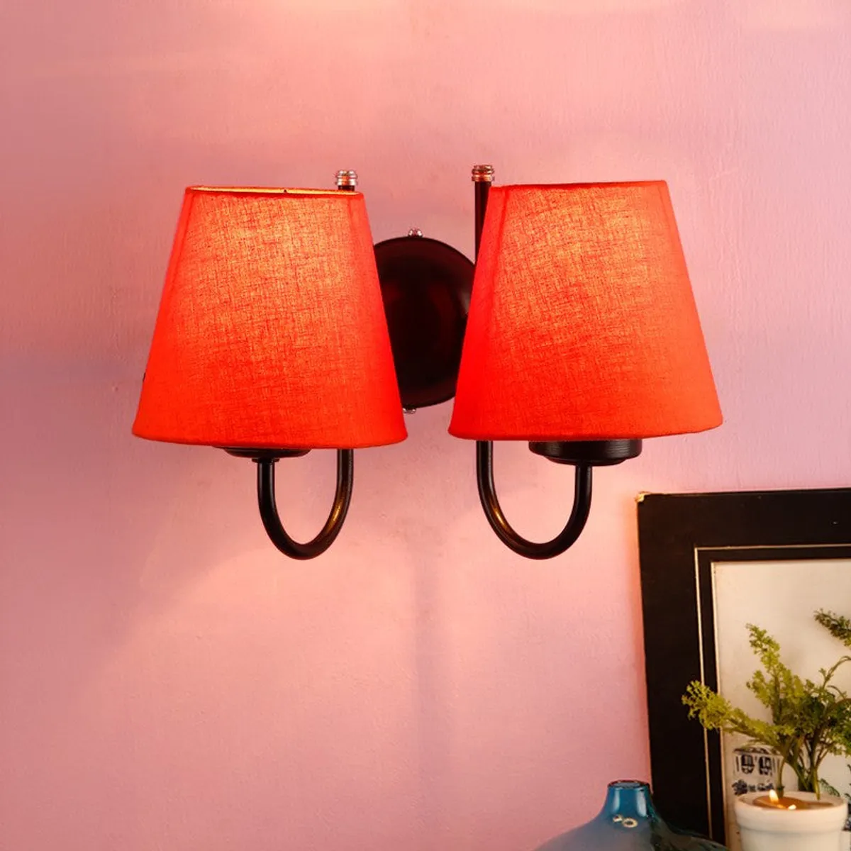 Close view of orange dual-shade wall lamp on a pink wall