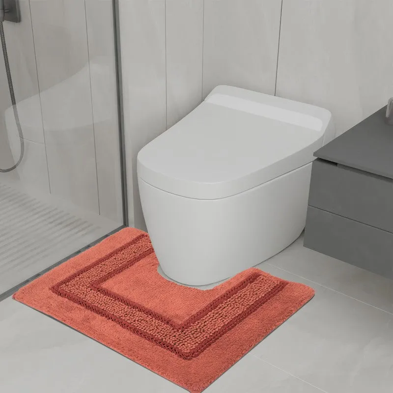 Orange anti-skid bath mat placed beside a toilet in a modern bathroom