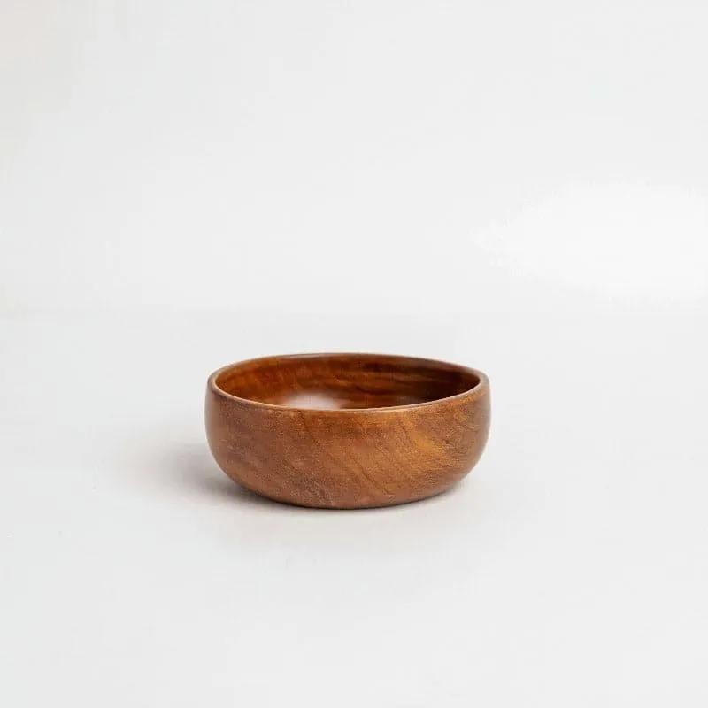 Single round brown wooden bowl on a light background