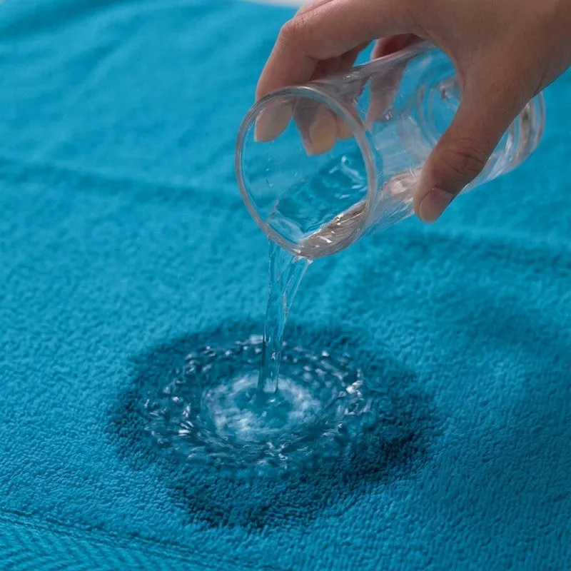 Water being poured onto a blue towel close-up