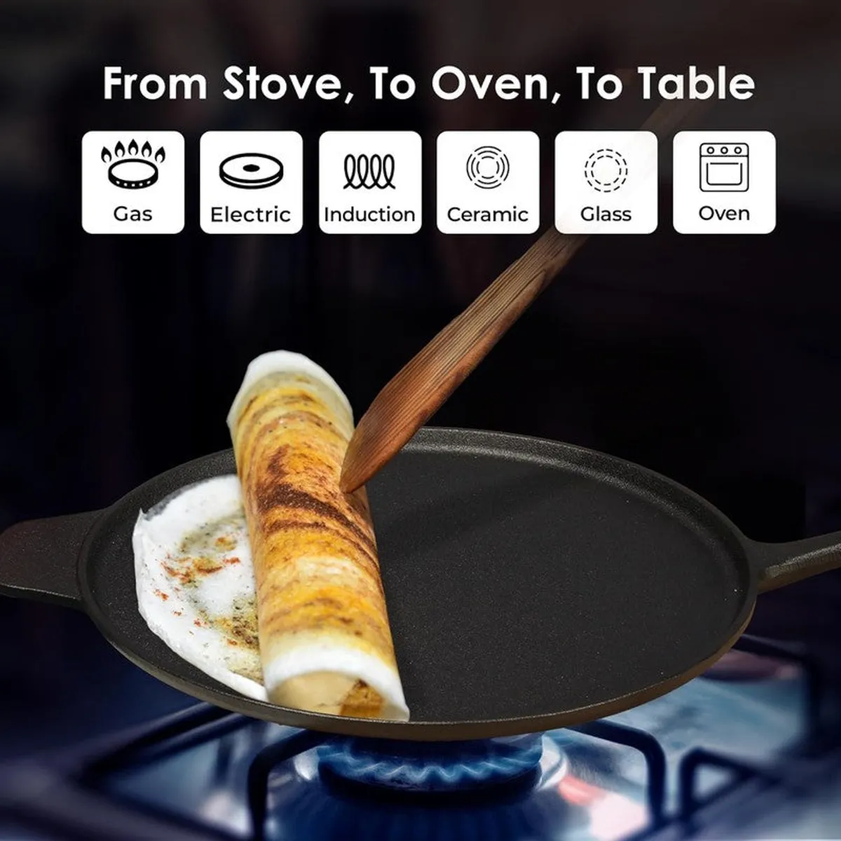 Black cast iron dosa tawa on a gas stove with a rolled dosa