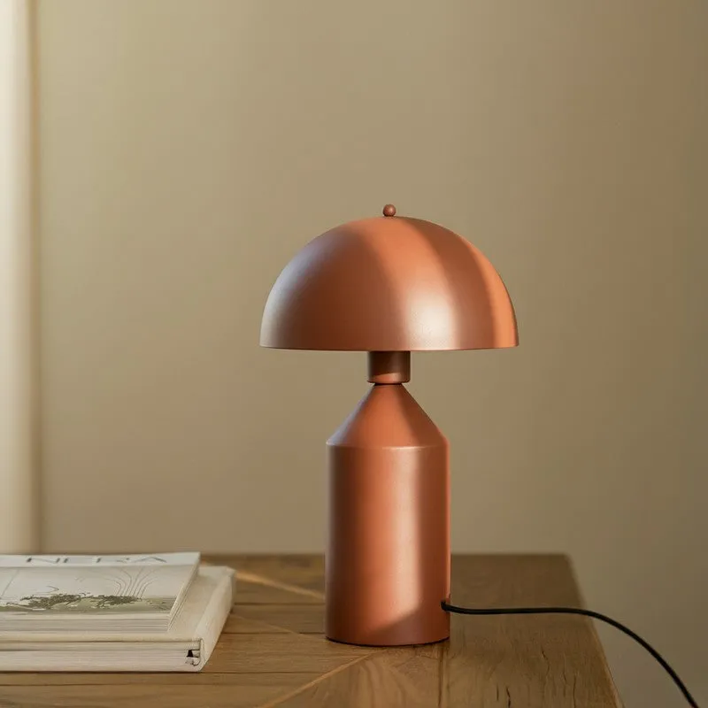 Brown metal table lamp on a wooden tabletop beside stacked books