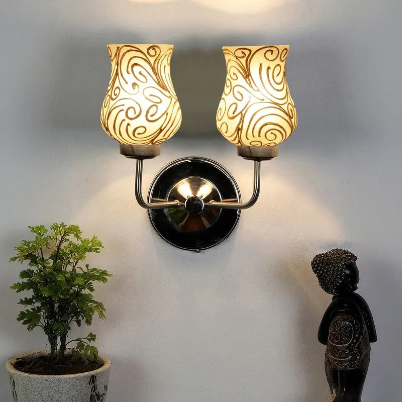 Lit dual wall lamp with white glass shades and gold swirl pattern