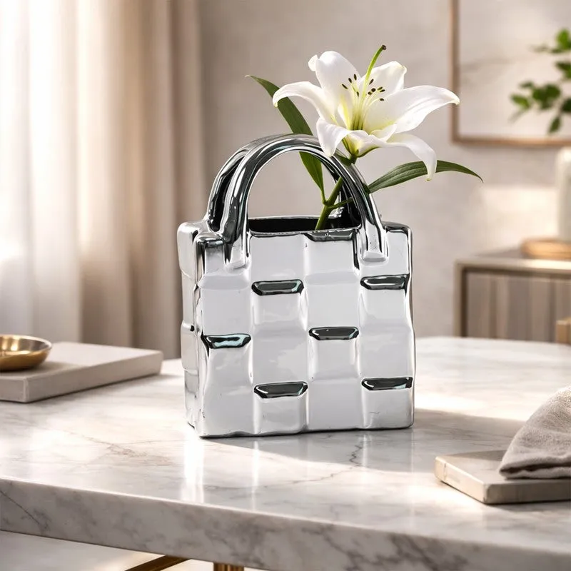 Silver handbag-shaped vase styled with a white lily on a marble surface