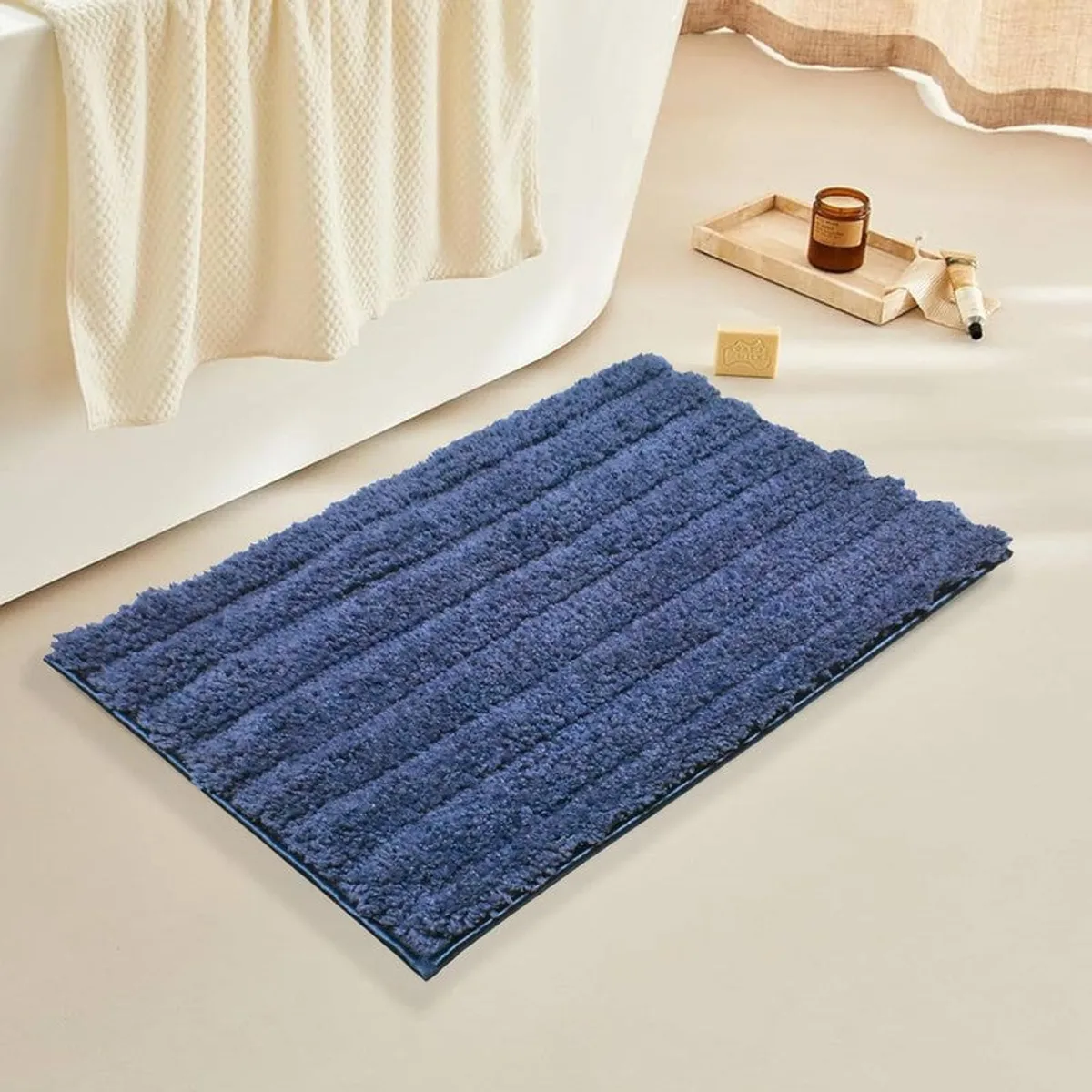 Deep blue rectangular striped bath mat beside a bathtub