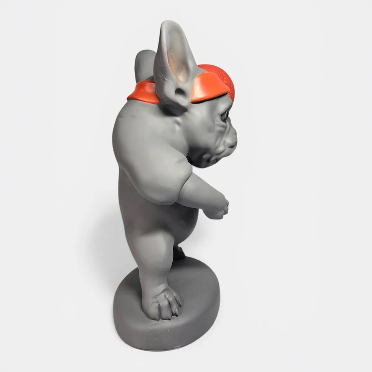 Side profile of the grey bulldog figurine with orange headband
