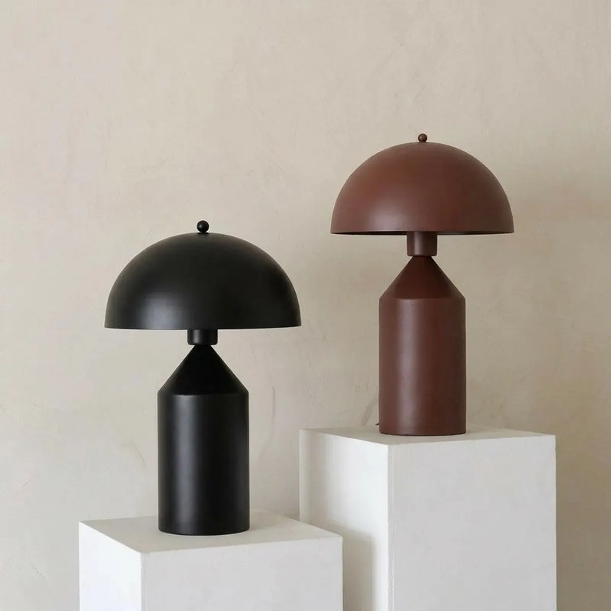Brown and black dome-shaped table lamps displayed on white pedestals