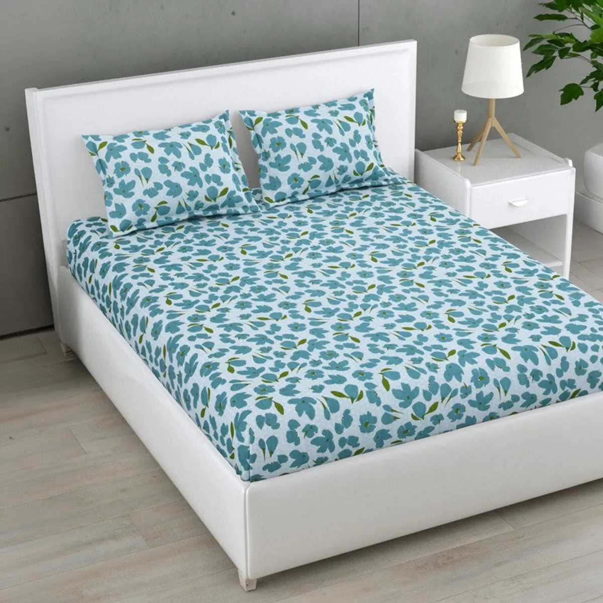 Angled view of blue floral bedsheet and matching pillows on a white bed