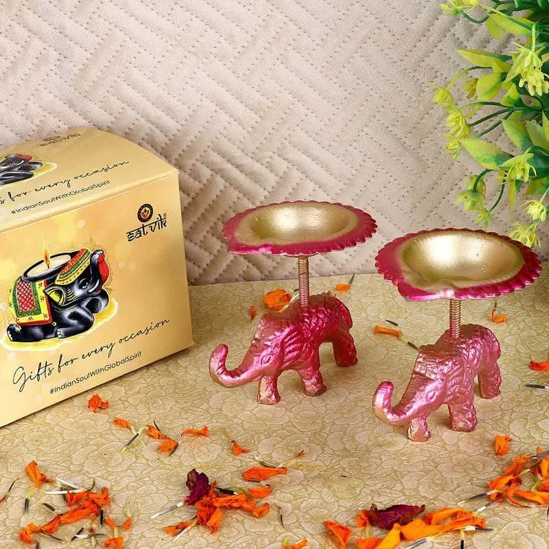 Two pink elephant tealight holders placed beside a gift box on a tabletop