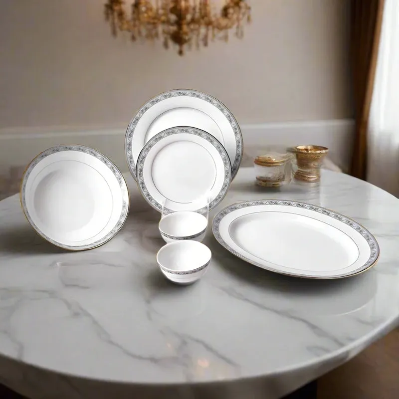 White porcelain dinner set with ornate blue and gold floral borders displayed on a dining table.