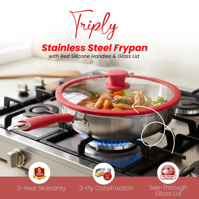 Silver triply frying pan with red handles and a clear glass lid on a hob.