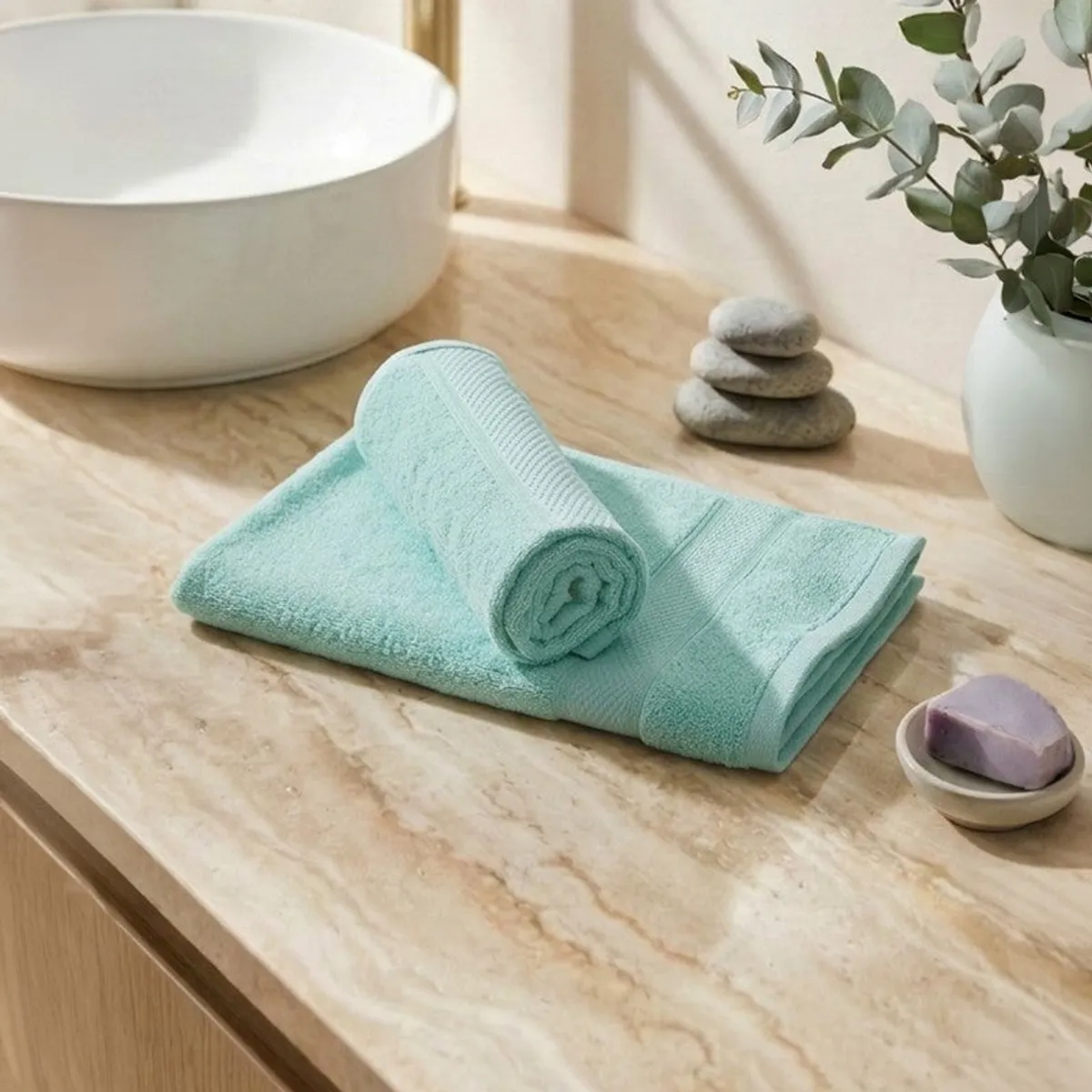 Rolled and folded sea-green hand towels on a bathroom counter