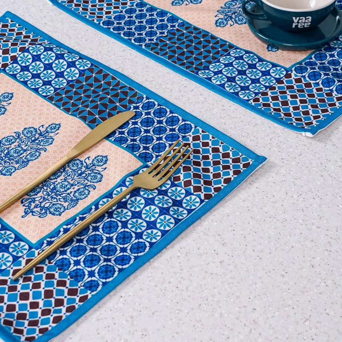 Blue and beige patterned table mats styled with cutlery and crockery
